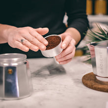 GROSCHE Milano stainless steel moka pot pouring freshly brewed espresso into a glass coffee cup