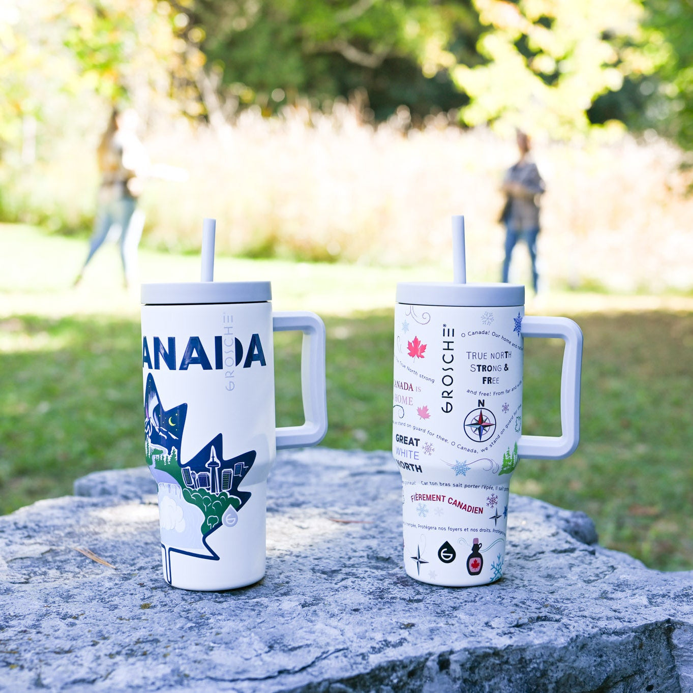 Two tumblers with designs on a stone surface outdoors