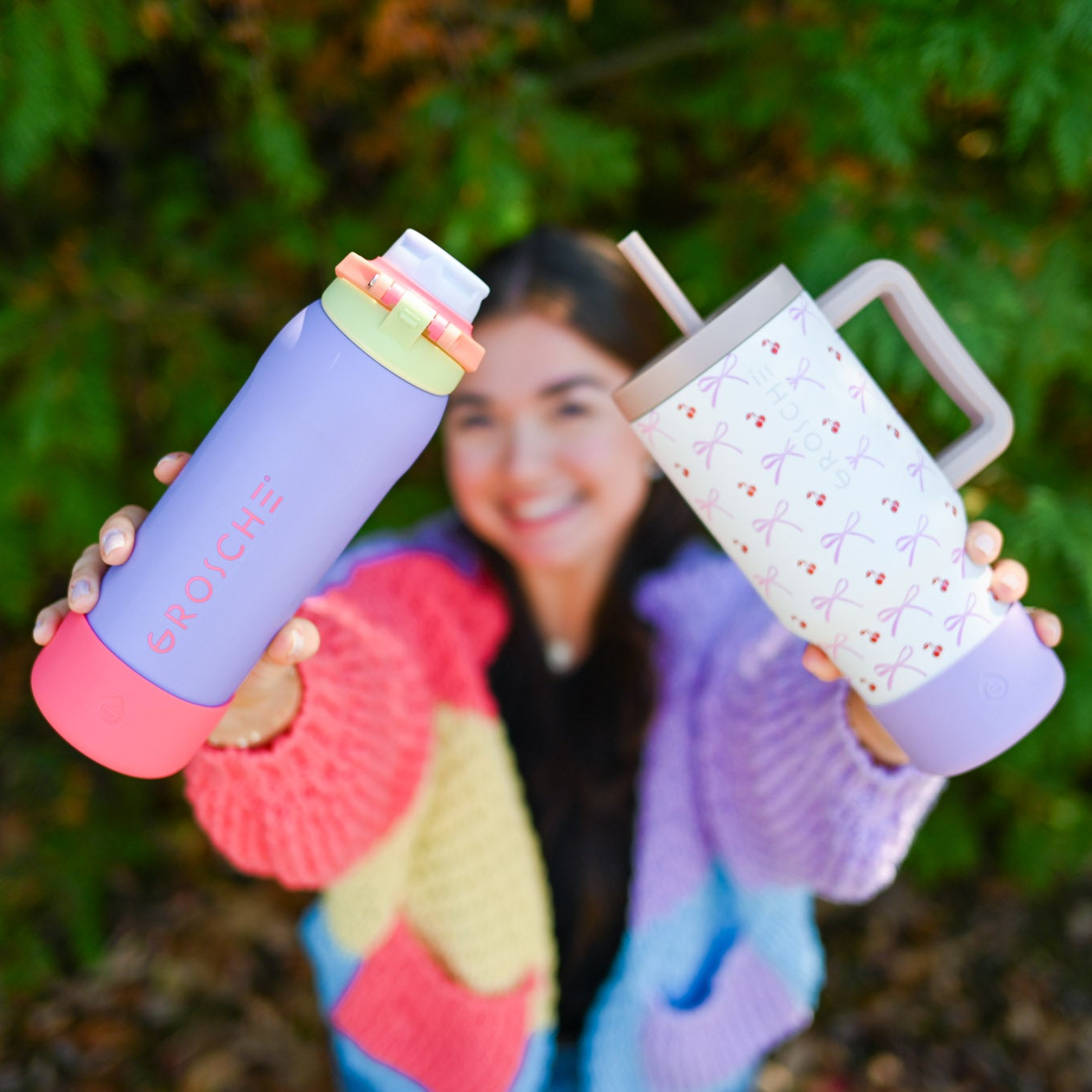 A woman holding two colourful water bottles with the Bottle Booty on each one.