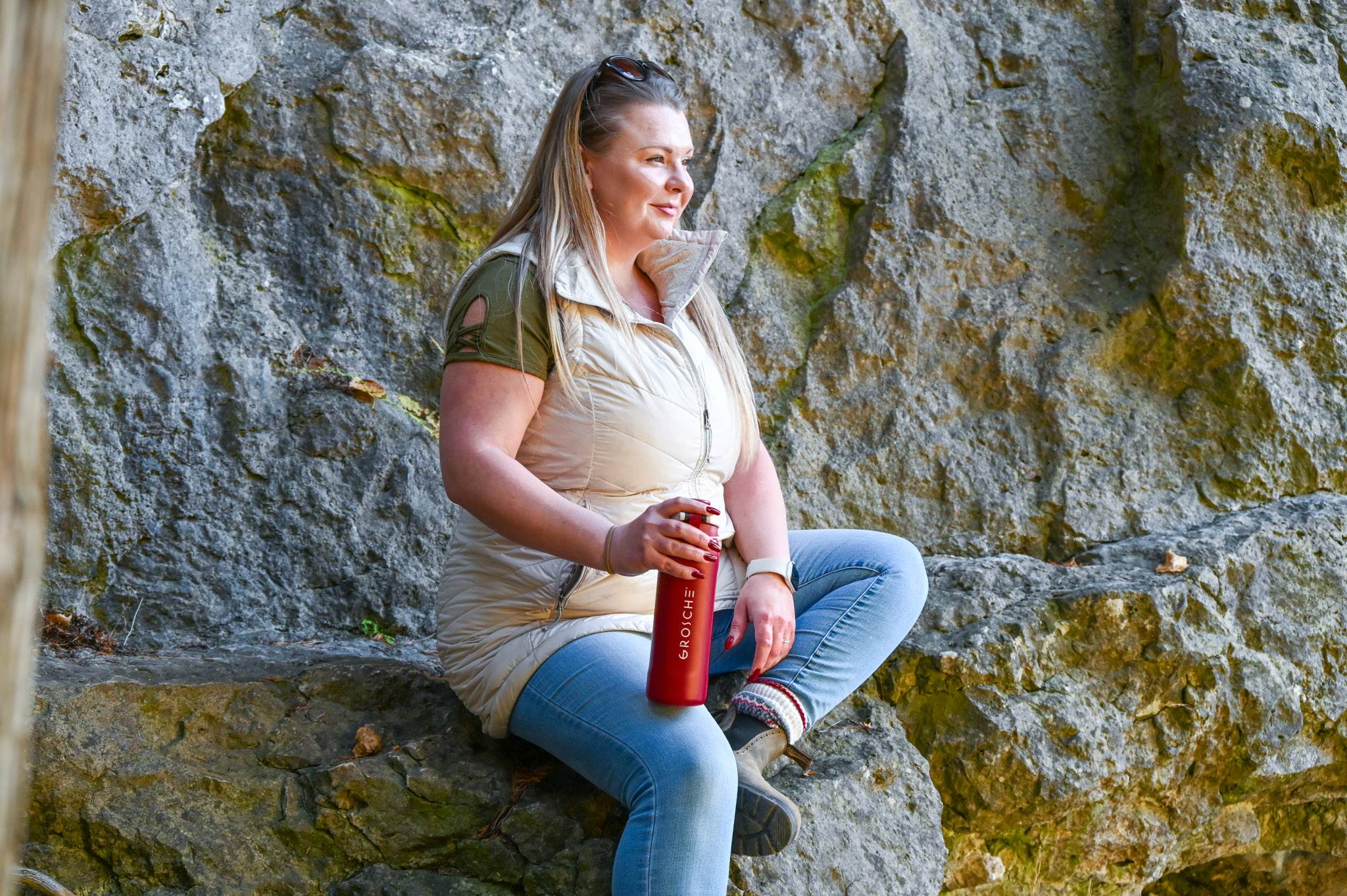 GROSCHE Kamloops Woman sitting on a rock wall holding a red bottle