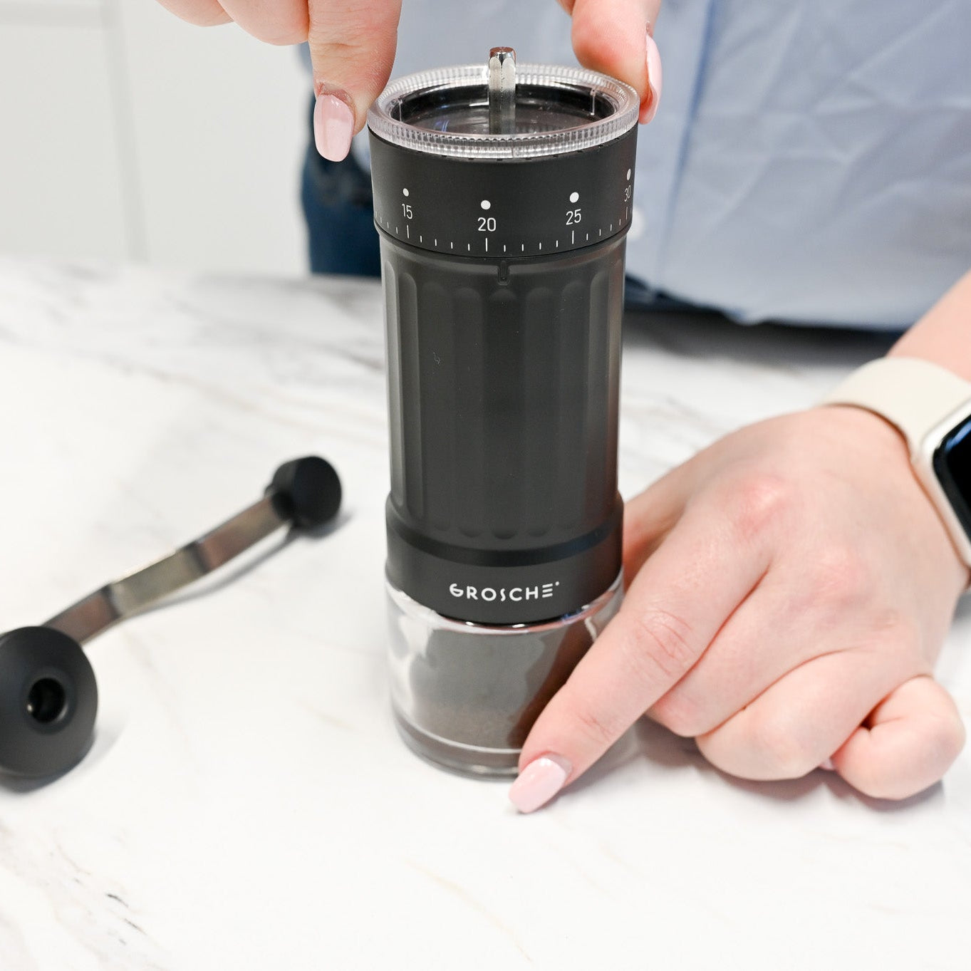 Person using a Grosche manual coffee grinder
