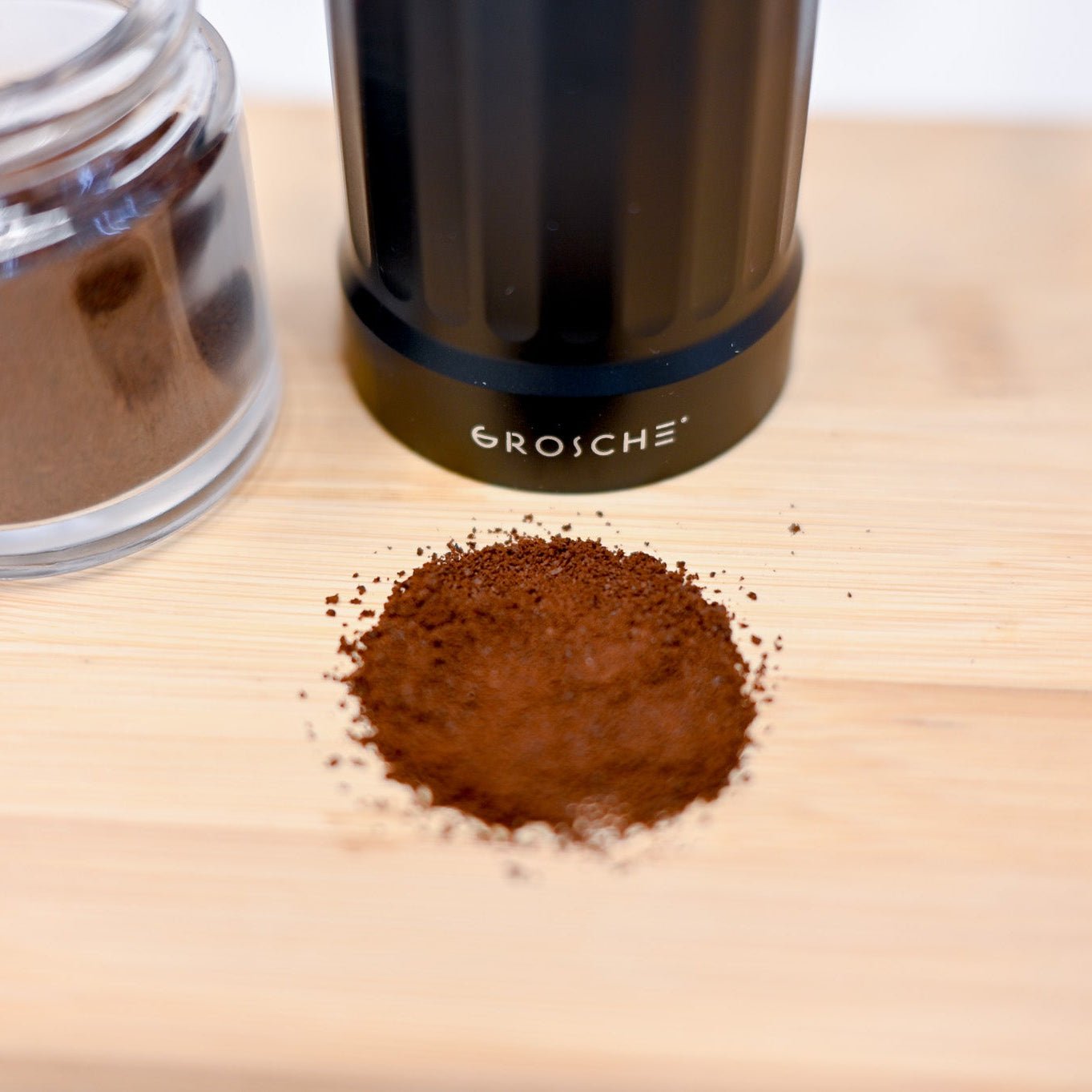 Coffee grinder with ground coffee on a wooden surface