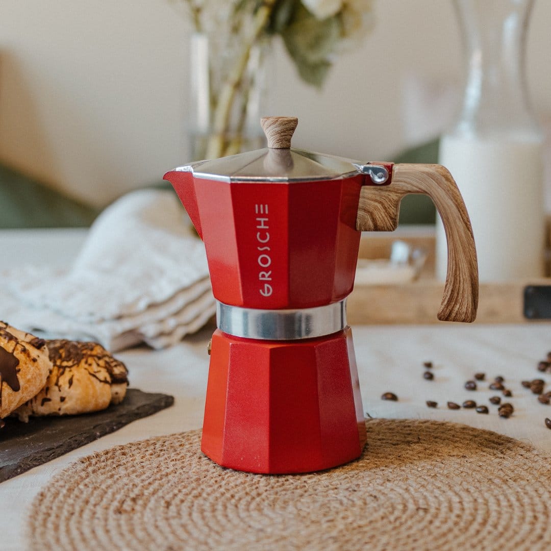 Red Grosche Milano mokapot sitting on counter with coffee beans