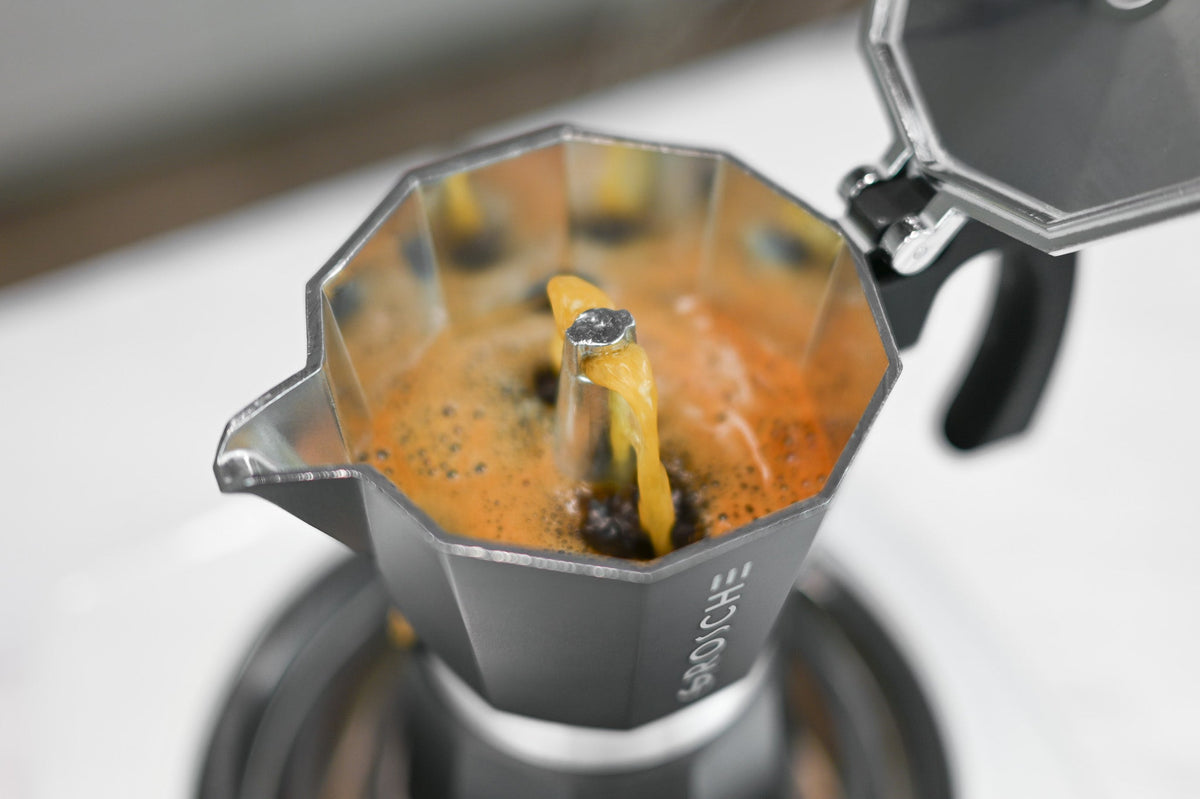 GROSCHE Milano stainless steel moka pot pouring freshly brewed espresso into a glass coffee cup