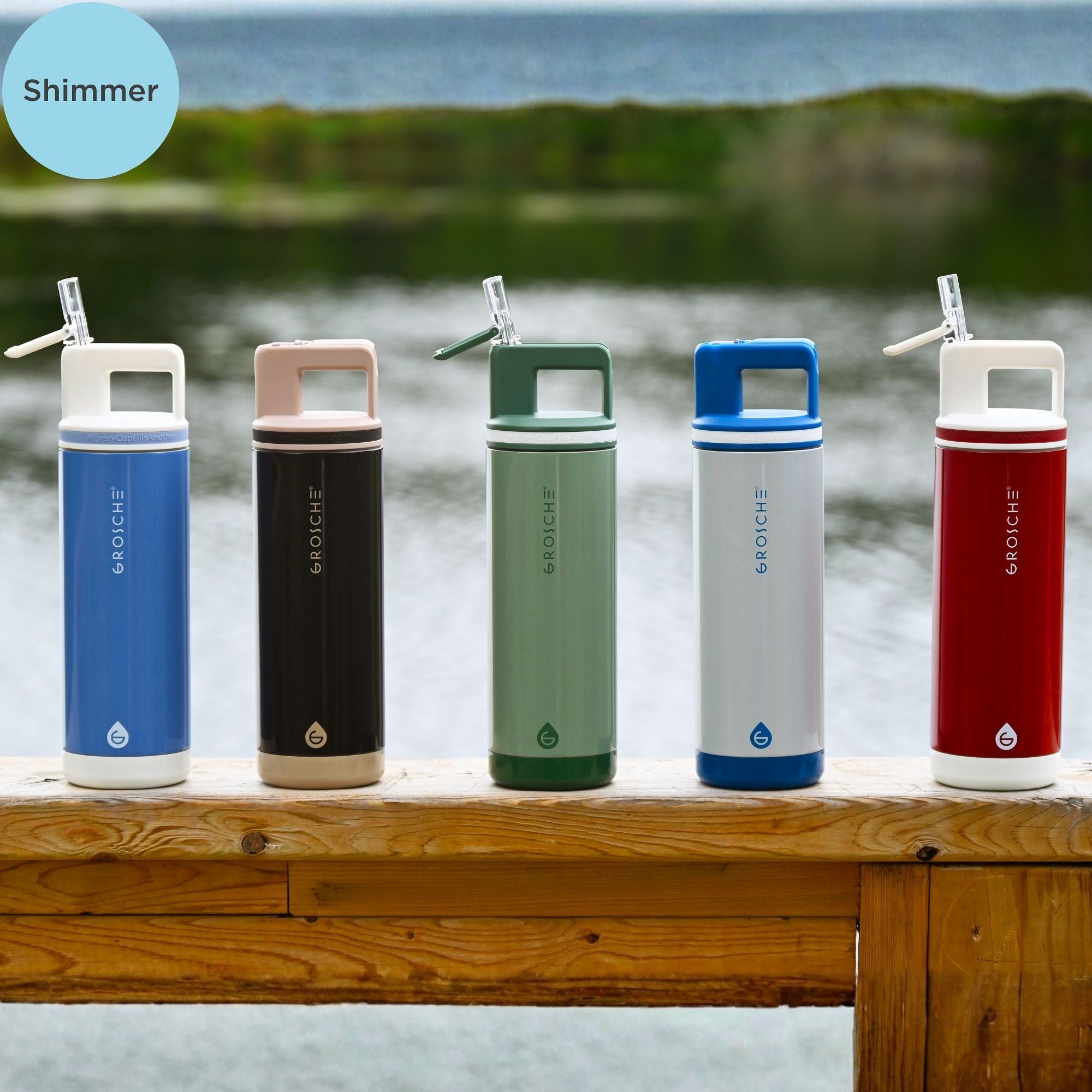 Five colorful water bottles with different finishes on a wooden bench by a body of water.
