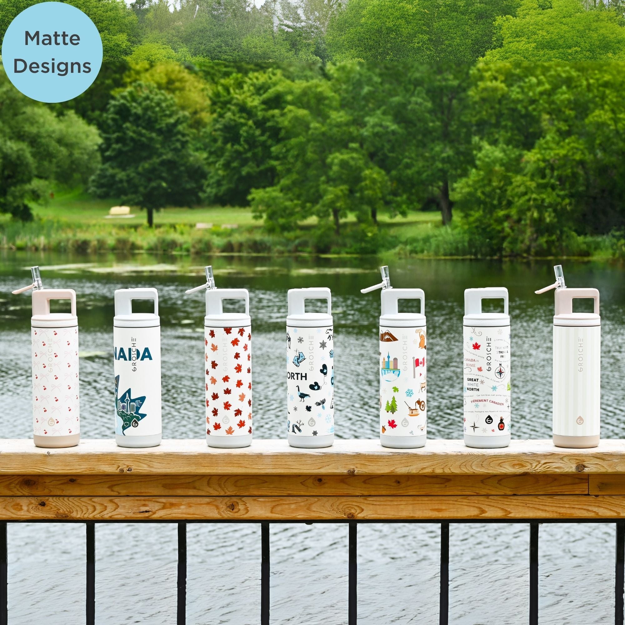 Set of water bottles with various designs on a wooden deck by a lake.