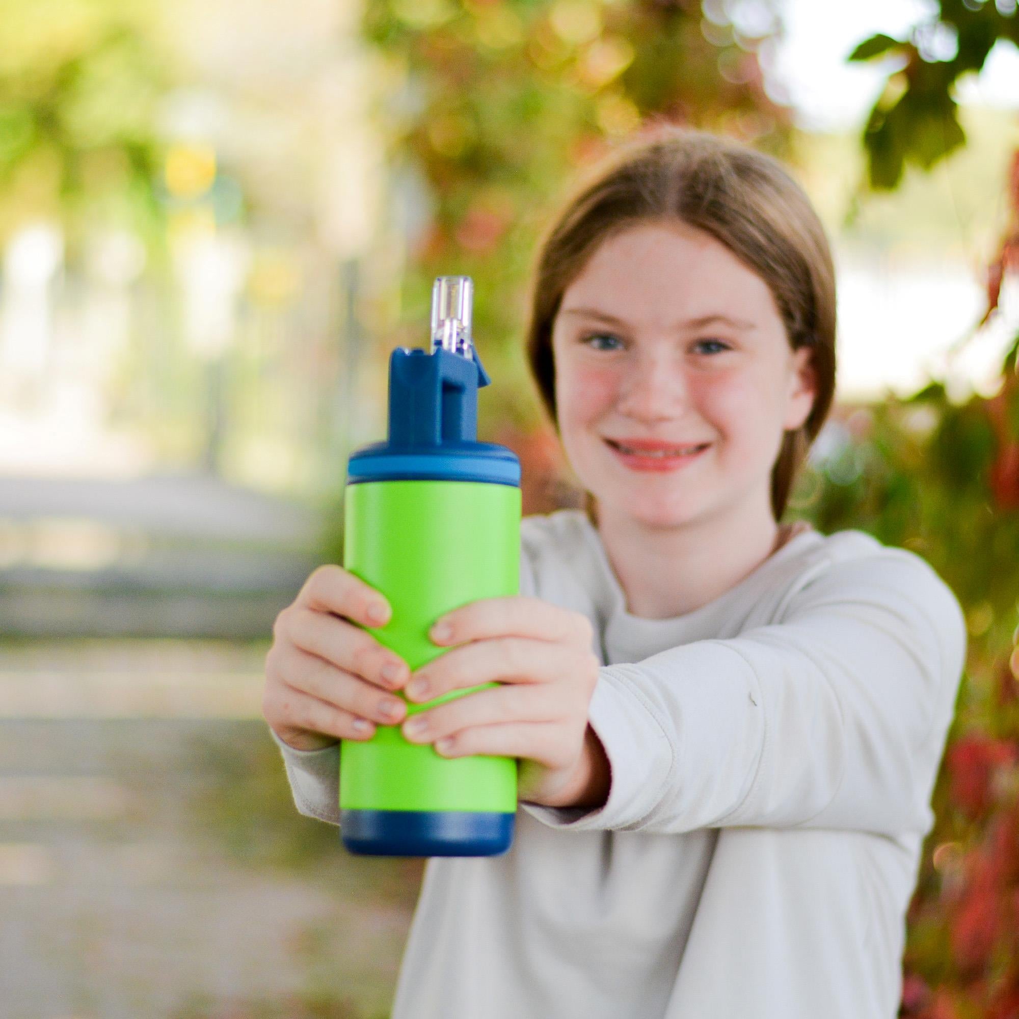 A girl standing outside, holding the Alpine water bottle in Dino Green. 