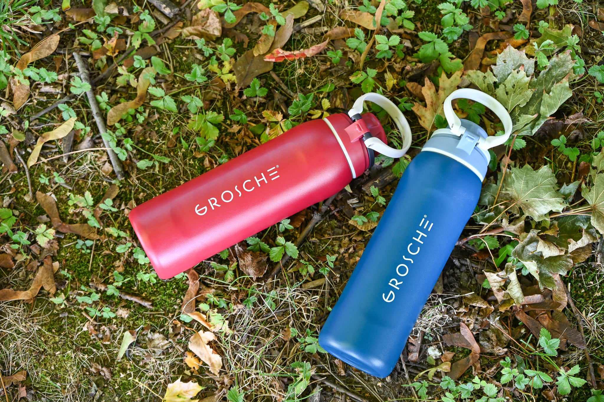 GROSCHE Kamloops a red and blue water bottle laying next to each other on the grass.
