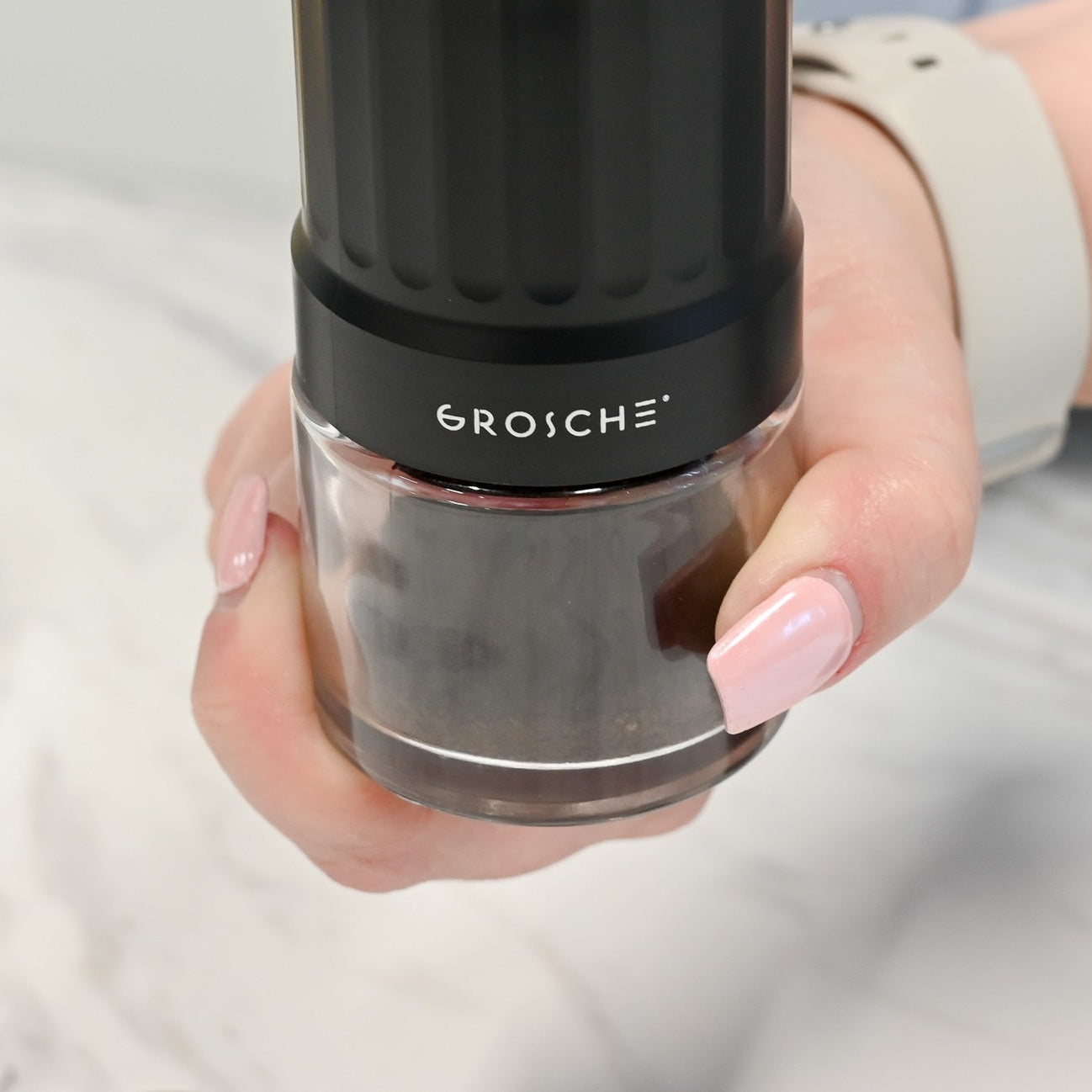 Hand holding a GROSCHE faucet handle with a blurred background