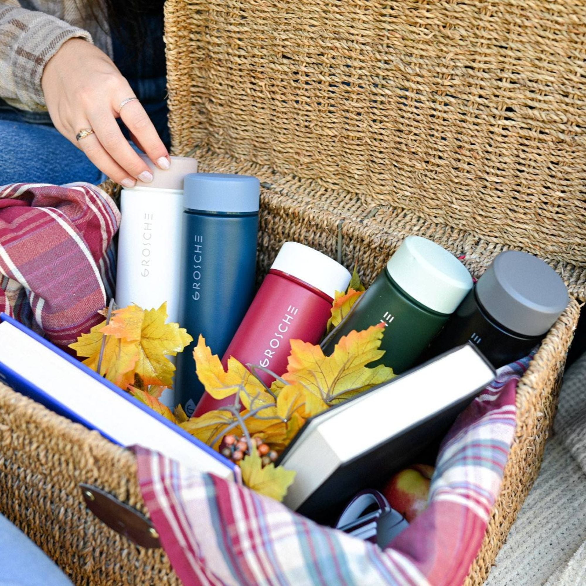 Collection of Grosche water bottles in a woven basket with autumn leaves